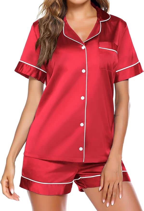 Woman wearing a matching red satin pajama set with white piping, consisting of a short-sleeve button-up top and shorts.