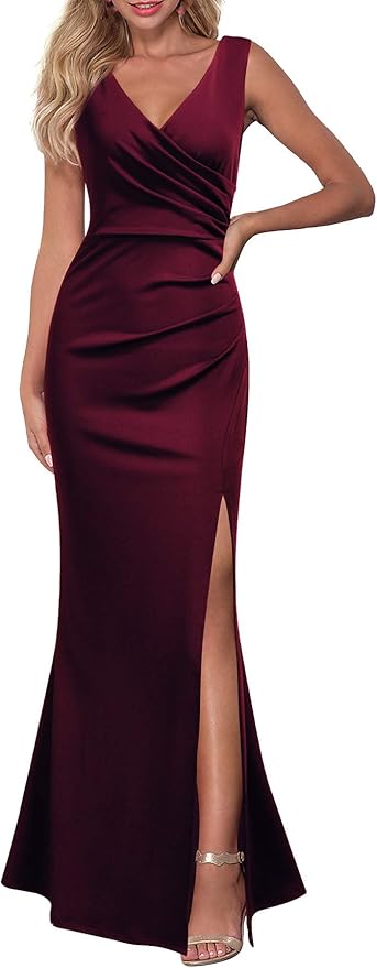 A woman wears a sleeveless, floor-length, dark burgundy gown with a V-neckline, ruched detail at the waist, and a thigh-high slit, paired with strappy heeled sandals.