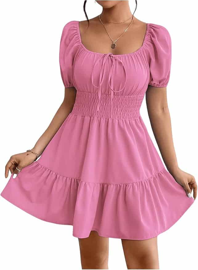 A woman wearing a short, pink, puff-sleeve dress with a smocked waist, square neckline, and ruffled hem.