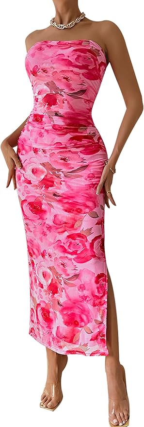 A woman wearing a strapless, form-fitting pink floral dress with a side slit, clear heels, a silver necklace, and rings.
