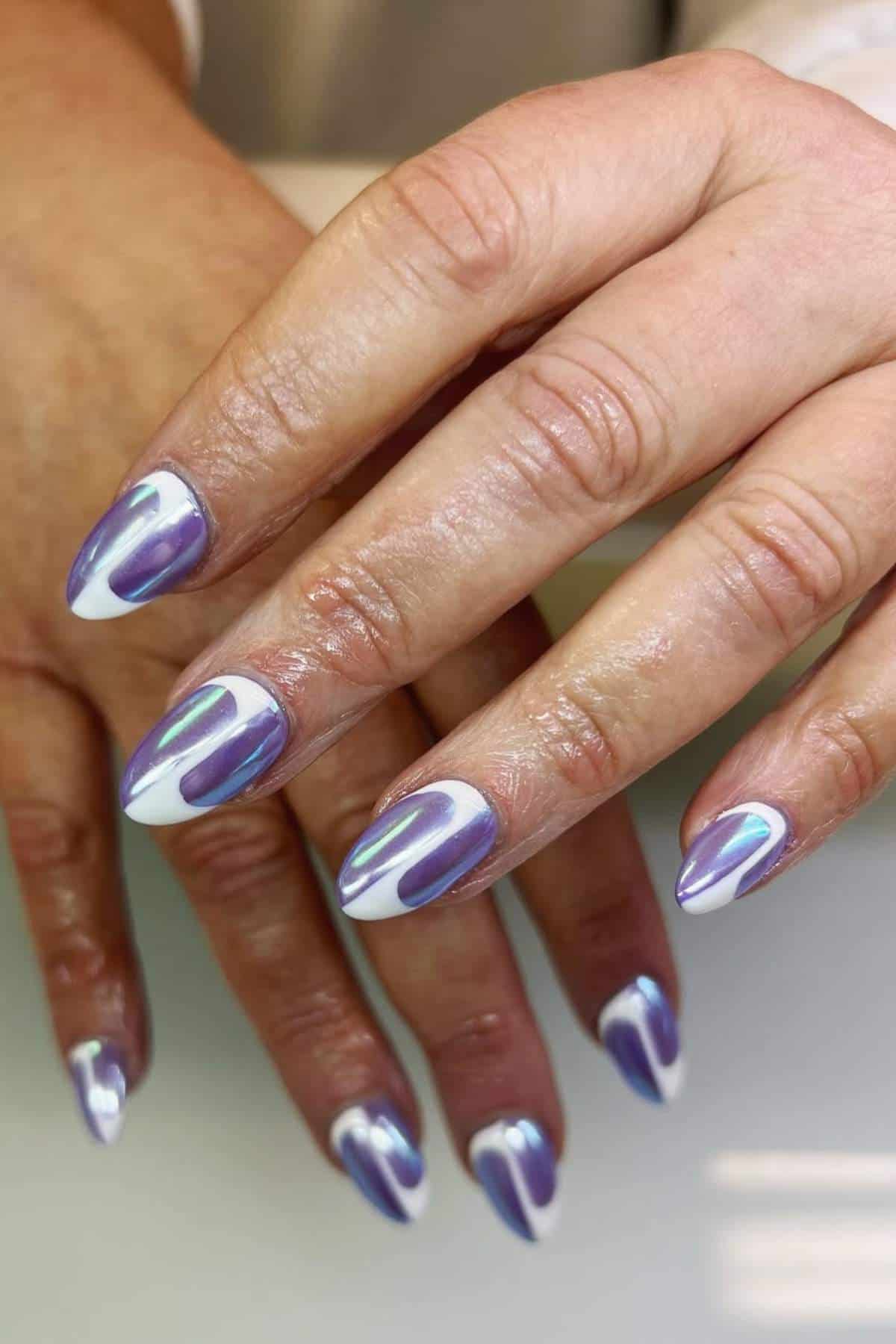 Hands with almond-shaped nails featuring a shiny purple and white abstract nail art design.