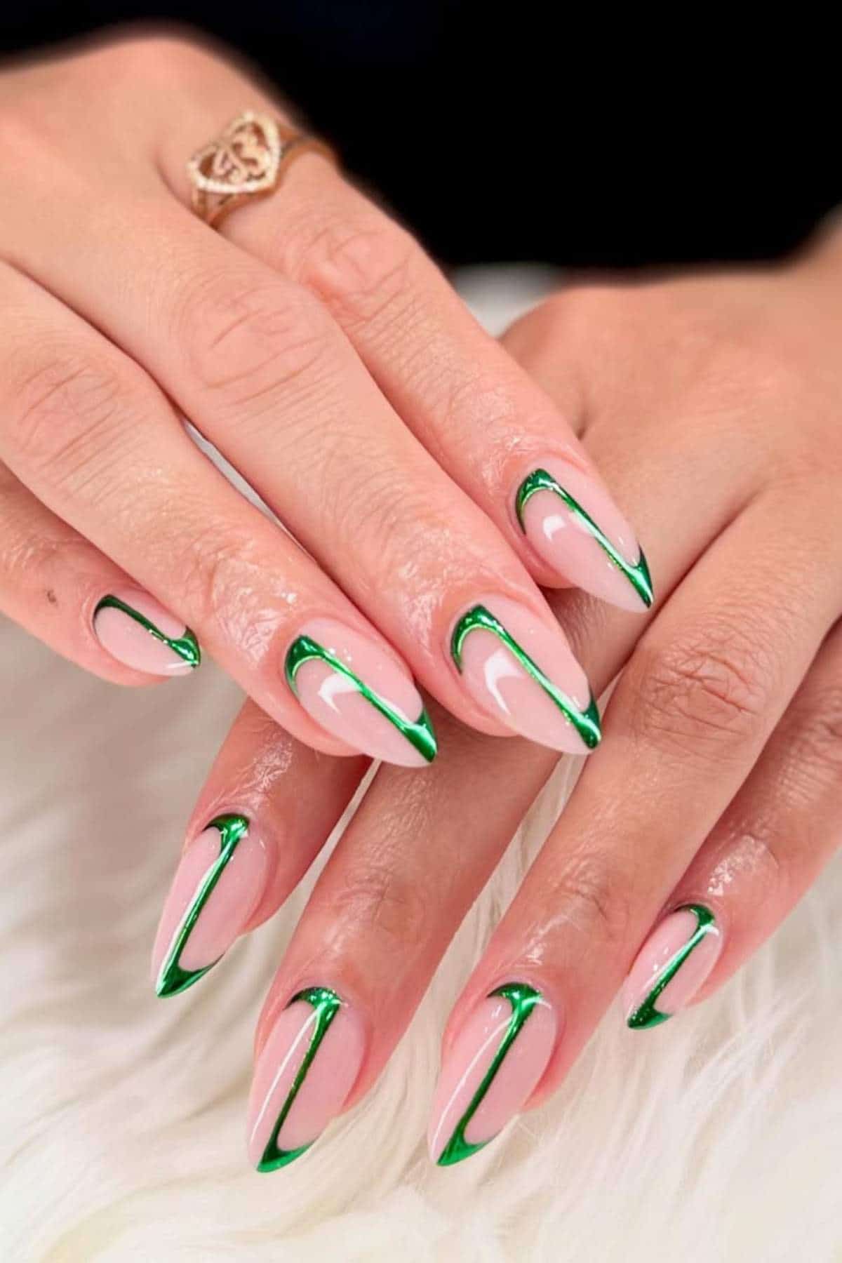 Hands with long, almond-shaped nails painted light pink with green and white abstract line designs on a white textured surface.