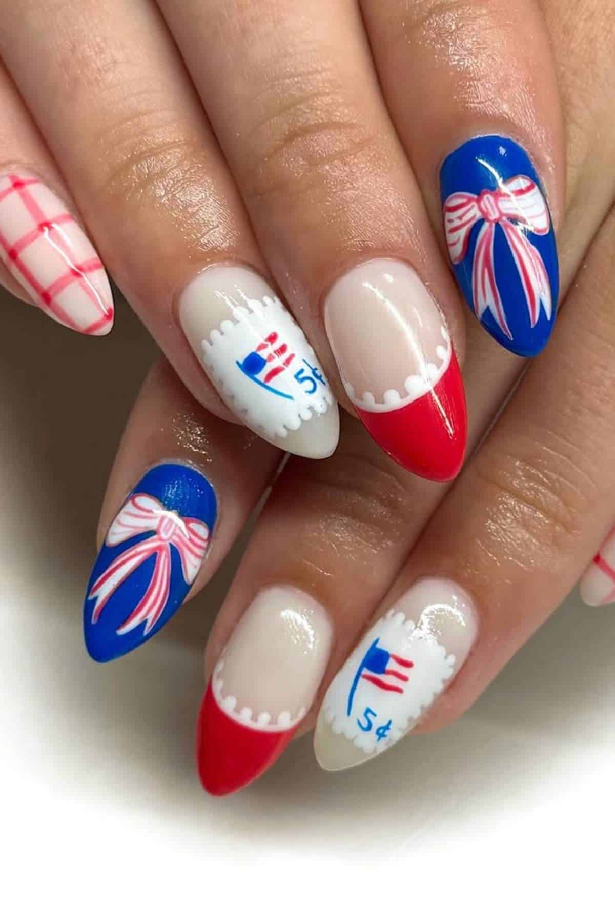 Close-up of fingernails with red, white, and blue nail art featuring bows, stamps, stripes, and plaid designs.