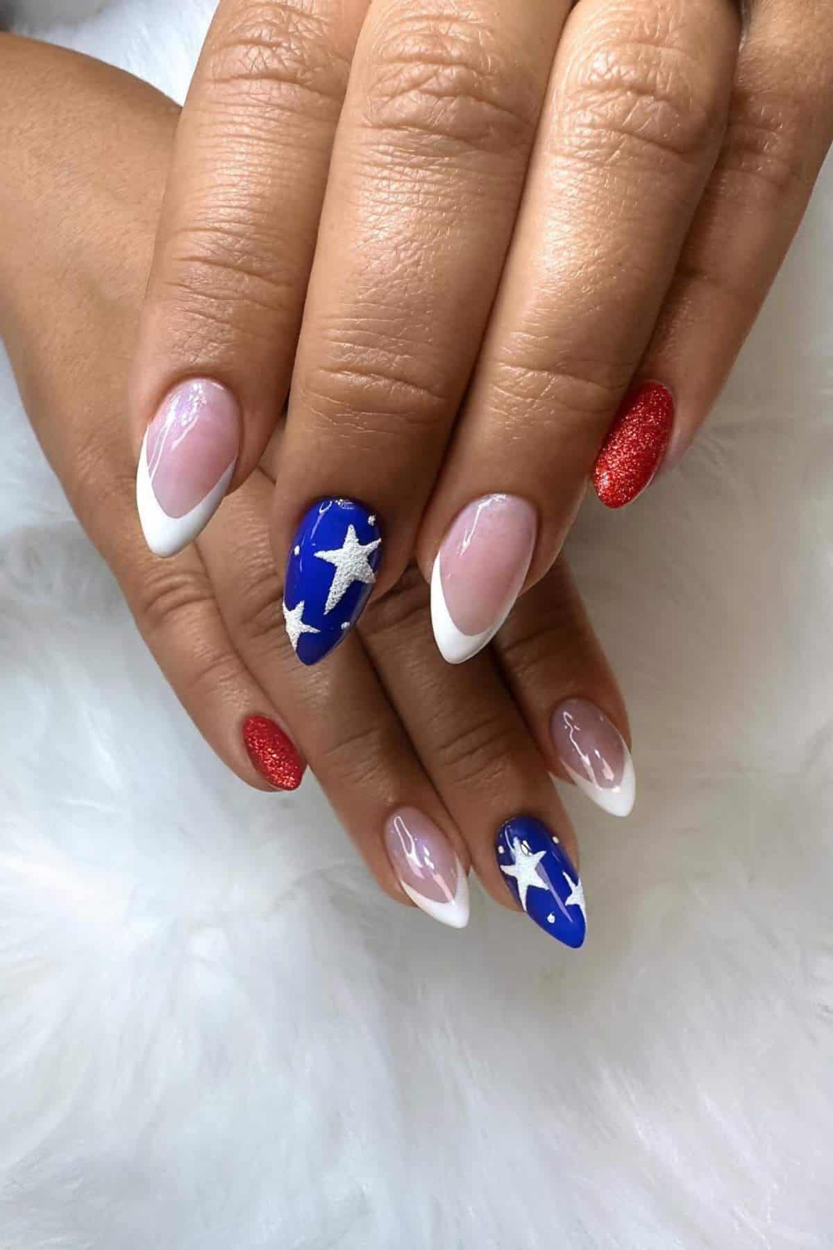 Hands with almond-shaped nails; some nails have French tips, others are painted red glitter, and two are blue with white stars.