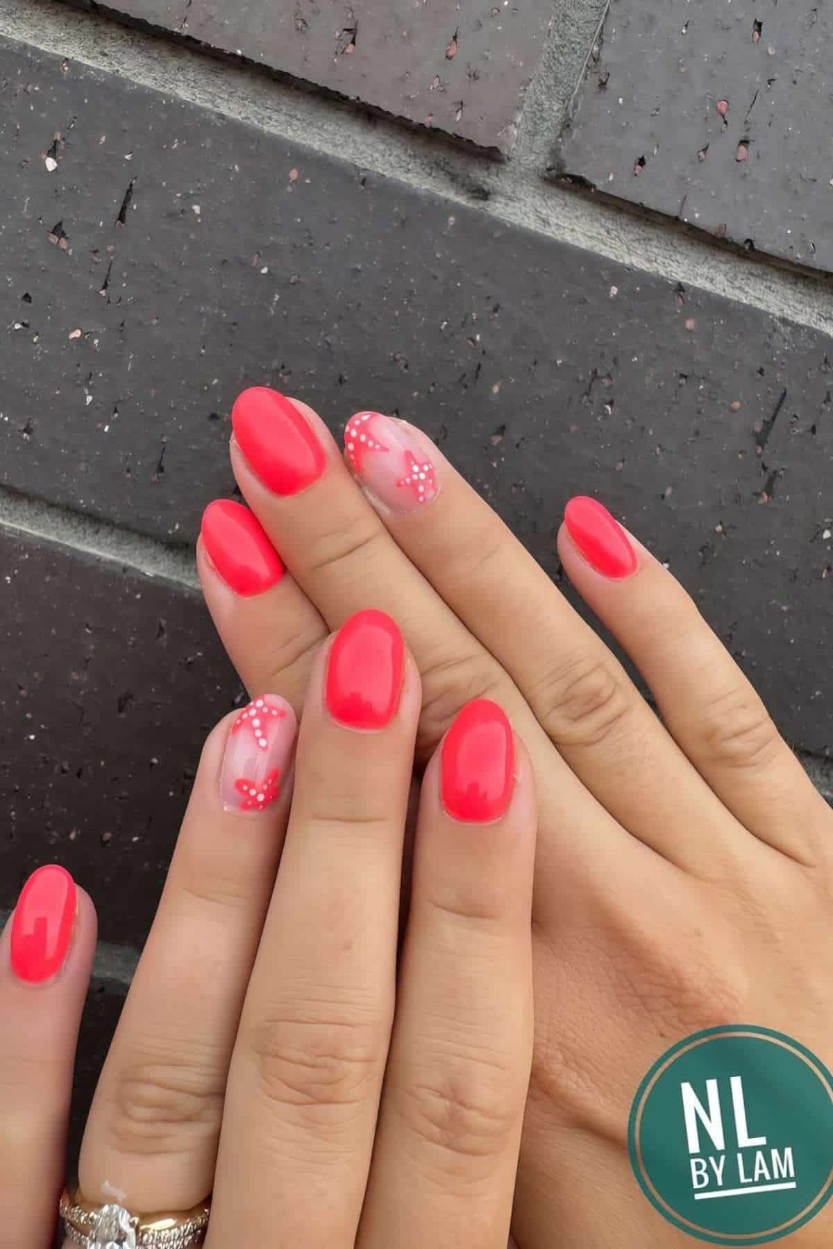 Two hands with short, oval-shaped nails painted bright red; two accent nails feature nude polish with red and white dotted designs.