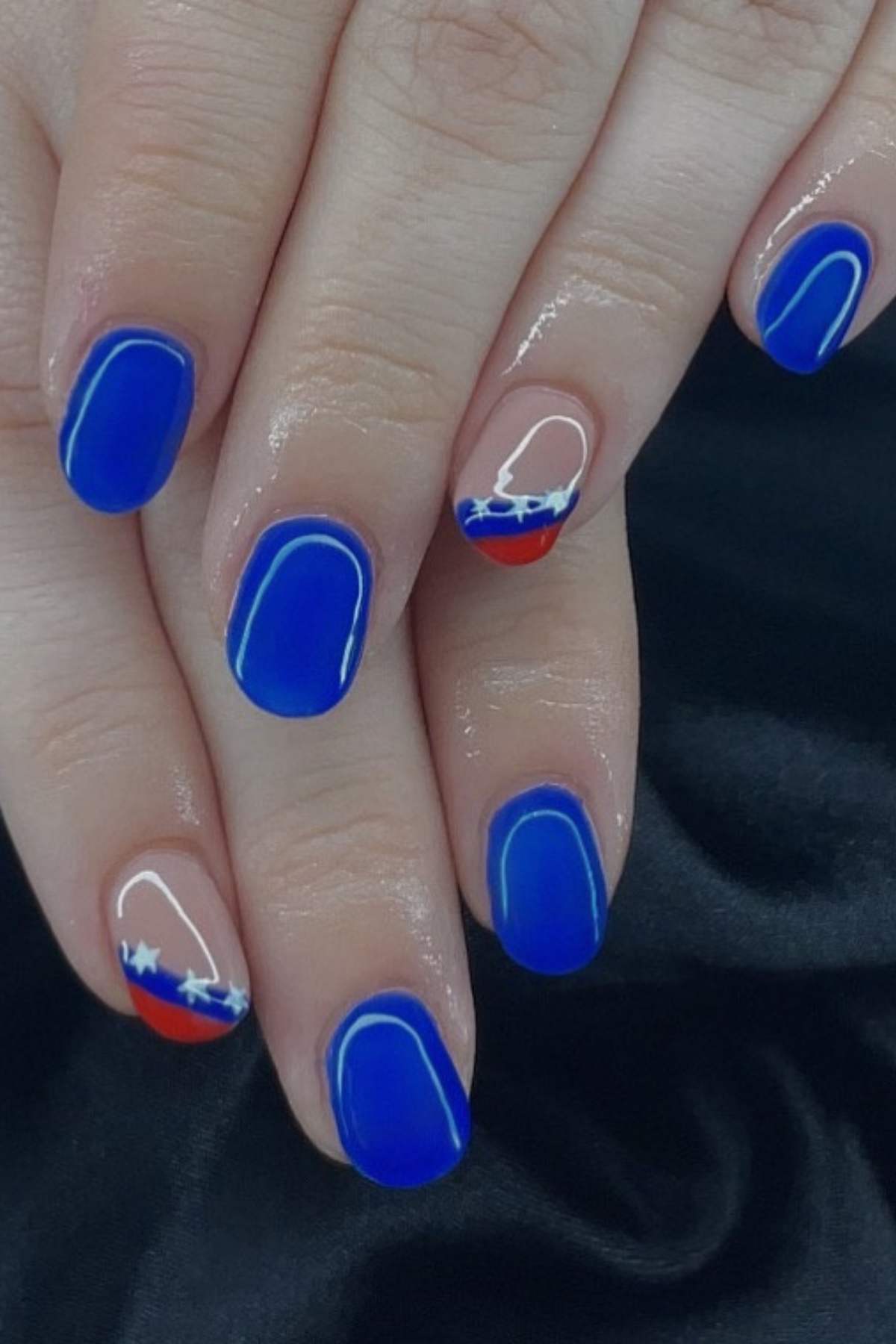 Hands with blue manicured nails; two nails feature red tips, white outlines, and star designs resembling the Venezuelan flag.