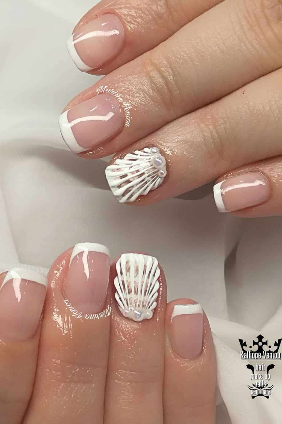 Hands with a French manicure; ring fingers feature a white seashell design with small pearl accents.