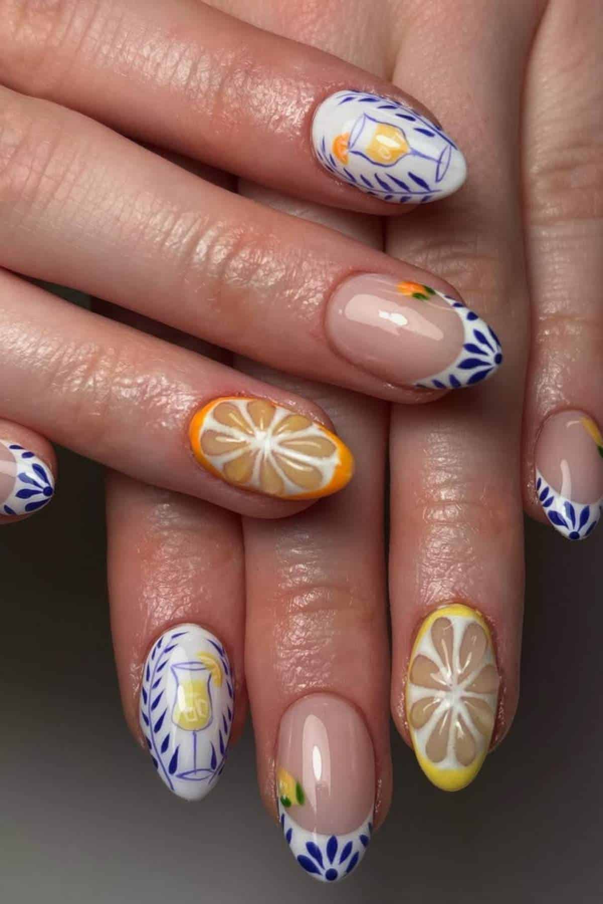 Fingernails with detailed nail art featuring blue geometric patterns, yellow lemons, lemon slices, and jars on a nude and white background.