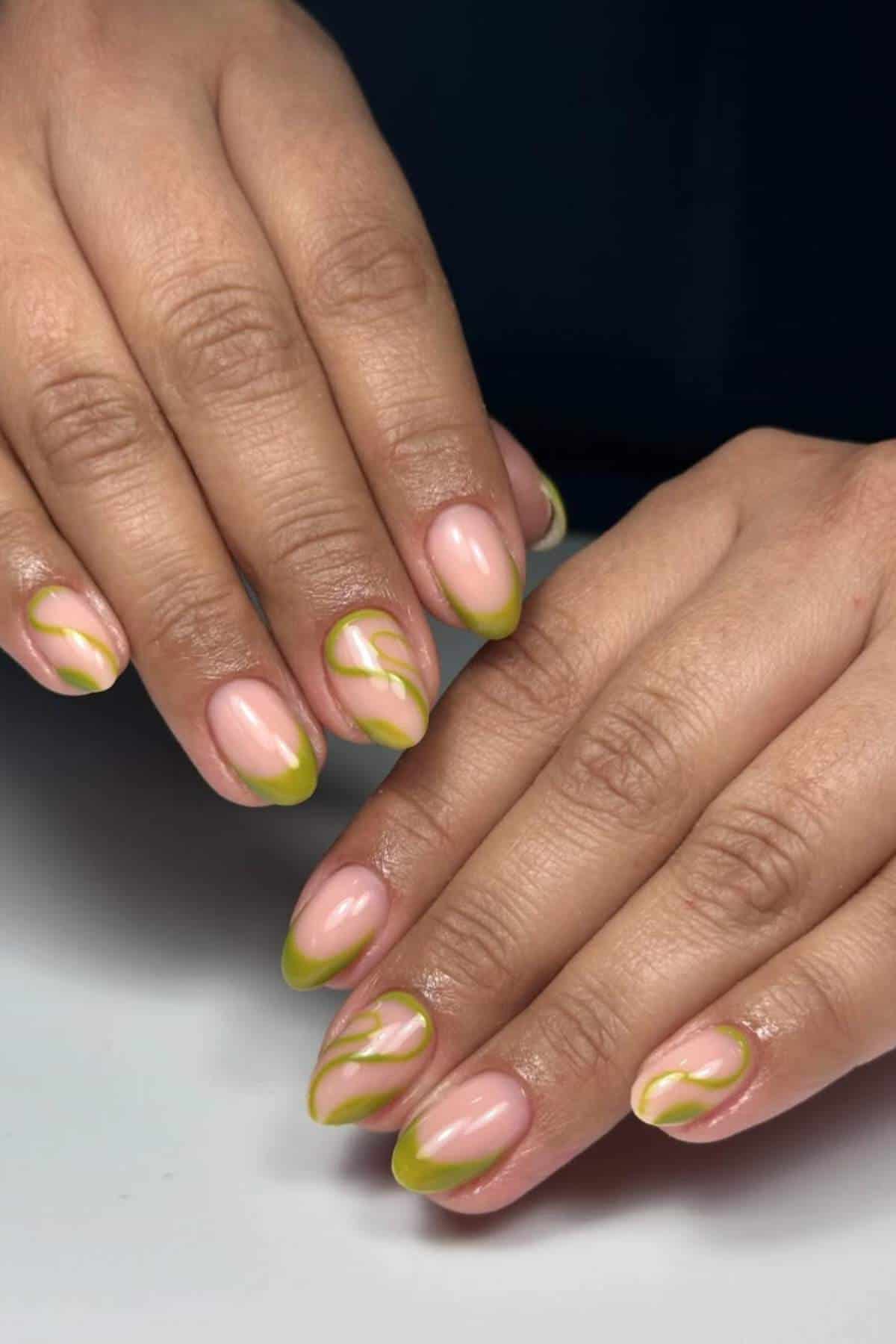 Two hands with short, almond-shaped nails featuring a nude base and green abstract swirl and French tip nail art design.