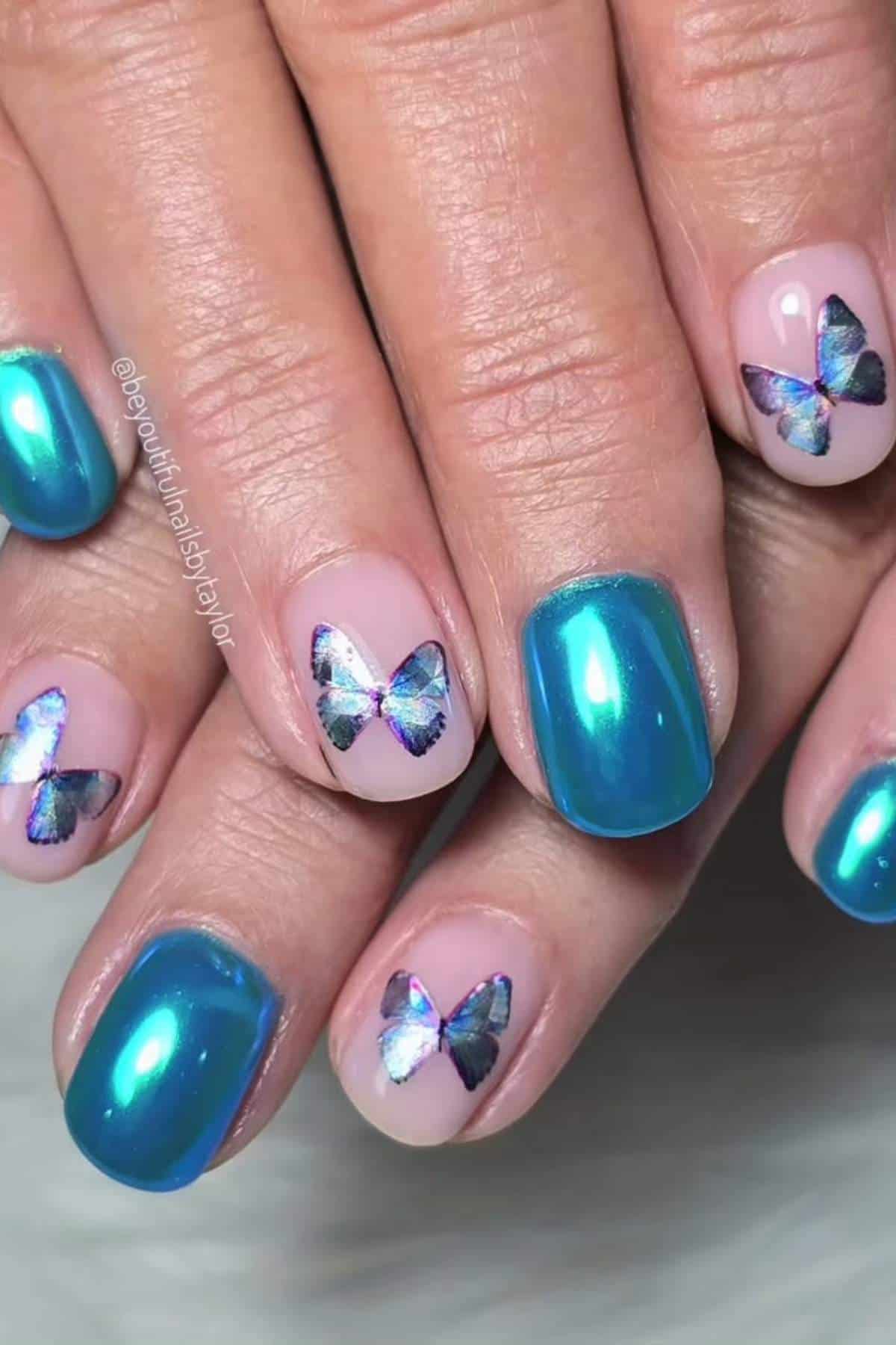 Close-up of hands with teal metallic nail polish and accent nails featuring butterfly decals on a nude base.