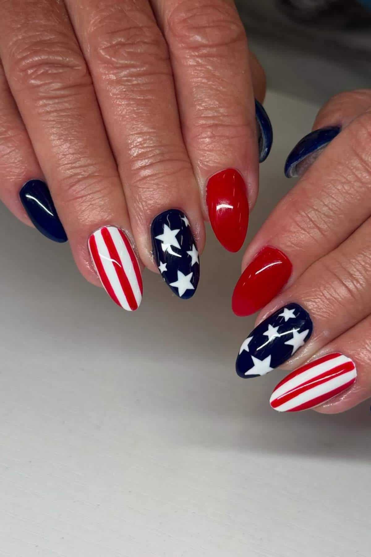 Hands with manicured nails featuring a patriotic theme in red, white, and blue with stars and stripes designs.