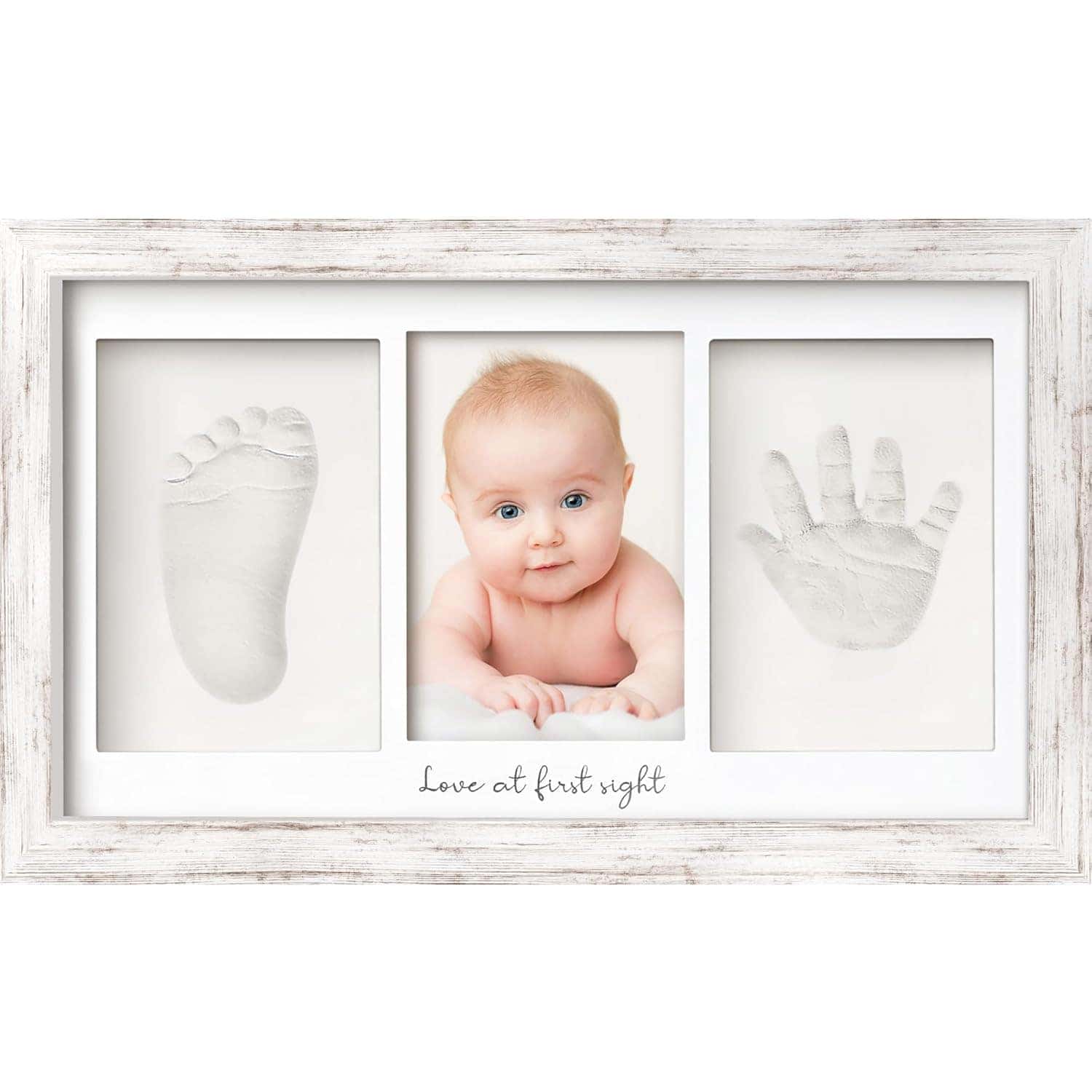 A framed display with three sections: a baby’s footprint mold, a baby’s portrait, and a baby’s handprint mold, with the text "Love at first sight" below.
