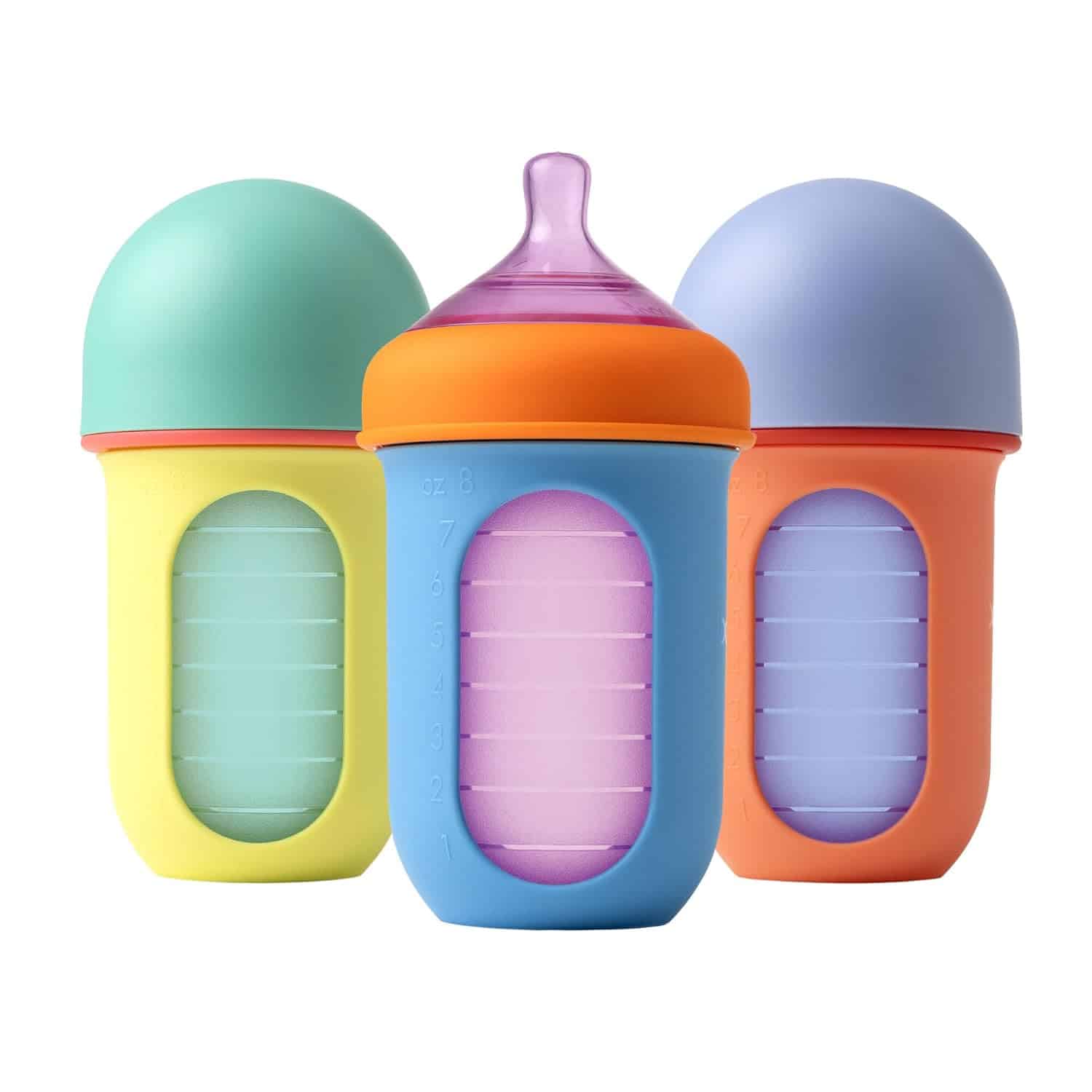 Three colorful silicone baby bottles with measurement markings; one has a purple nipple, and the others have rounded caps.