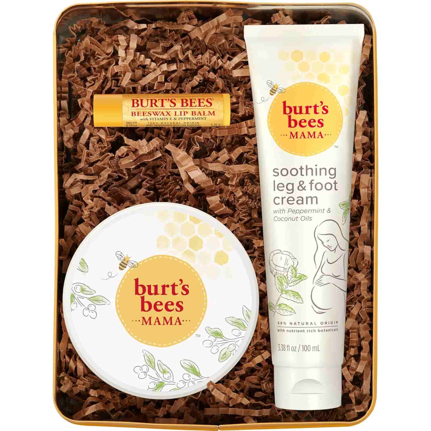 A Burt’s Bees gift set with beeswax lip balm, soothing leg & foot cream, and a round container, displayed on brown packing material in a box.