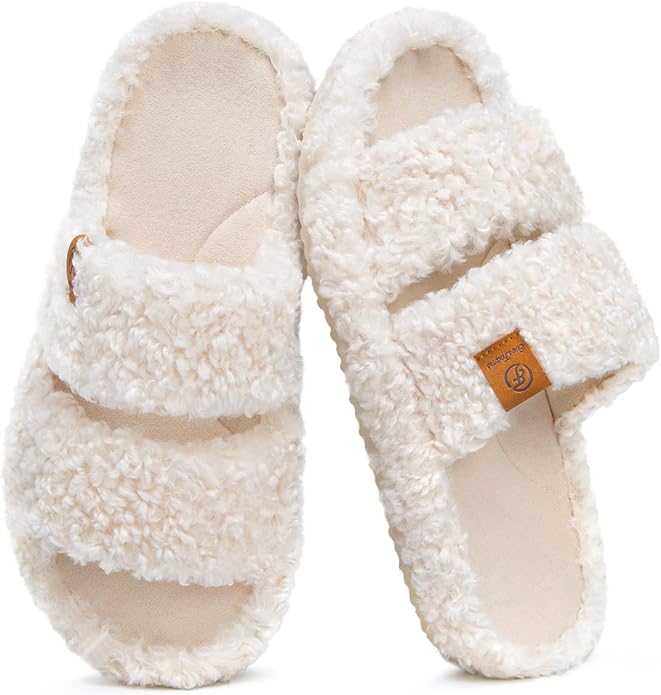 A pair of cream-colored, fuzzy, open-toed slippers with two wide straps and a soft, textured surface.