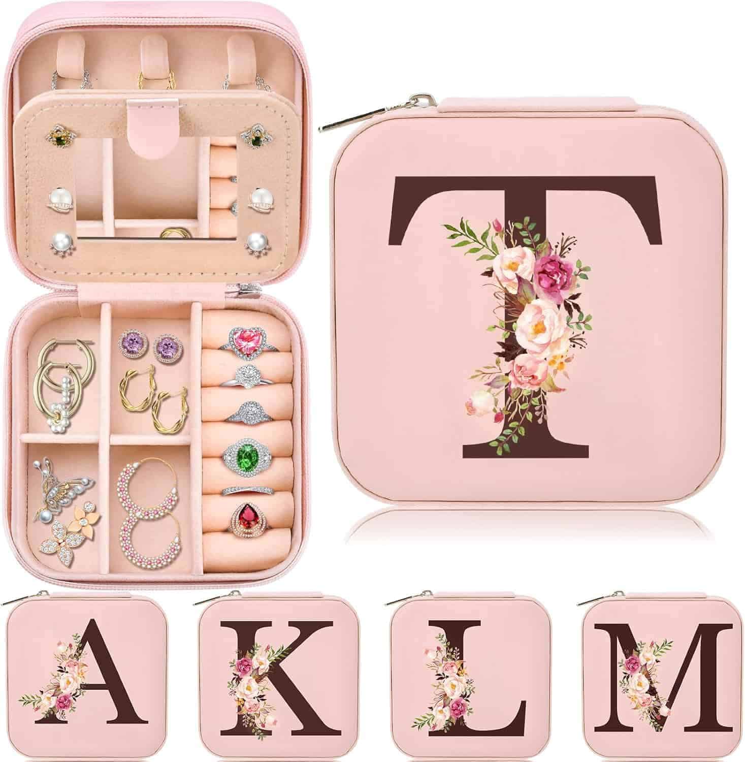Pink jewelry boxes with floral monogram letters (A, K, L, M, T), open box shows compartments for rings, earrings, and necklaces.