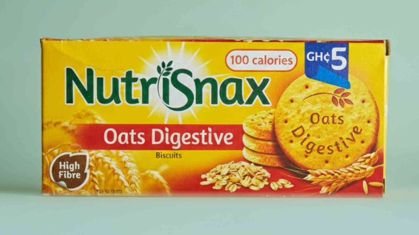A yellow box of Nutrisnax Oats Digestive Biscuits, labeled "100 calories," "High Fibre," and "GHC 5" with images of oats and biscuits on the front.