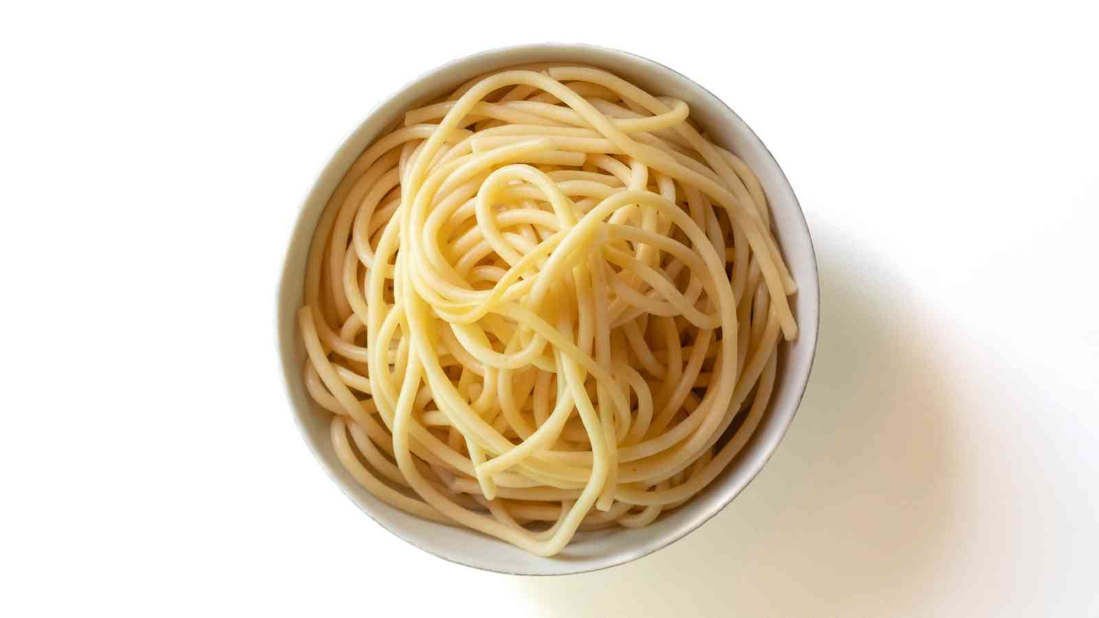A bowl of plain cooked spaghetti noodles on a white background, viewed from above.