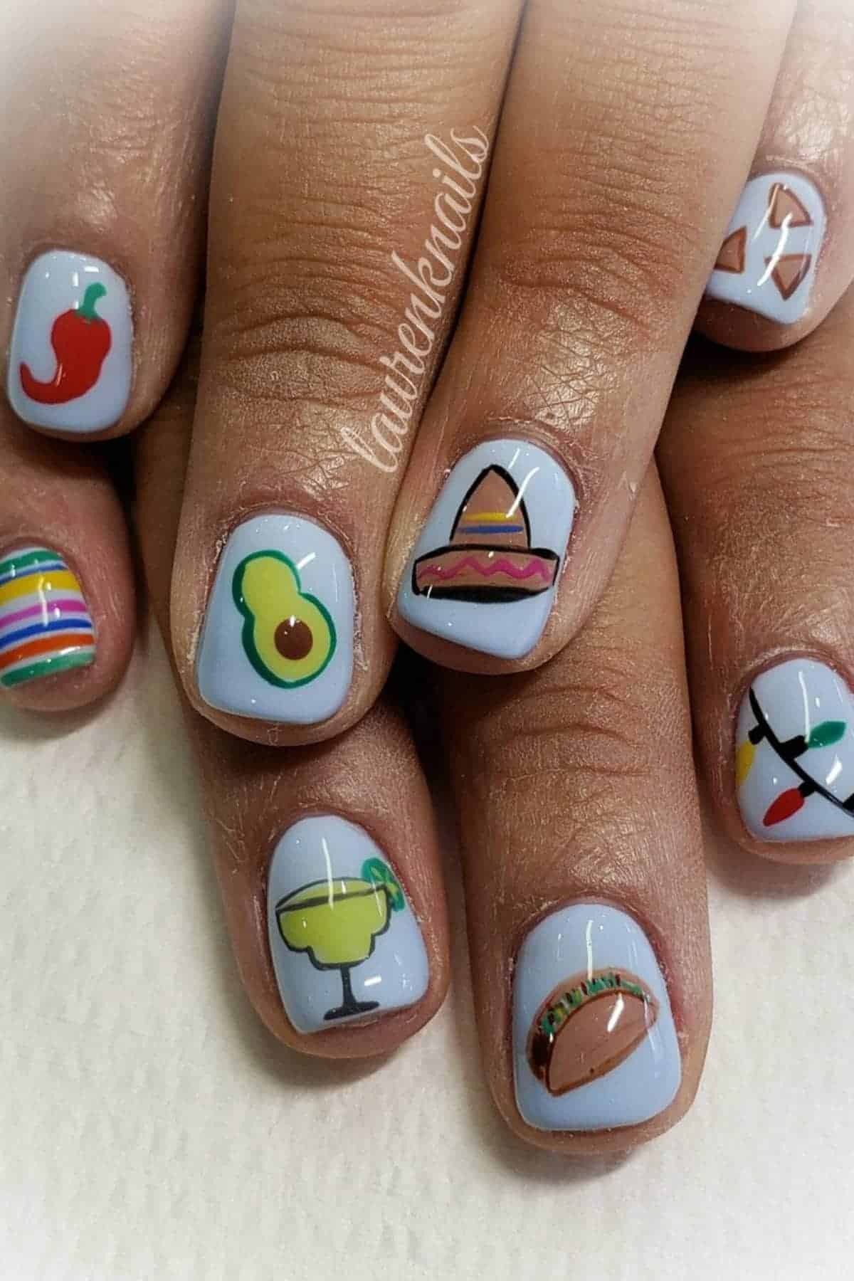 Fingernails painted with light blue polish and decorated with colorful designs including a chili pepper, avocado, sombrero, taco, margarita, piñata, and maracas.