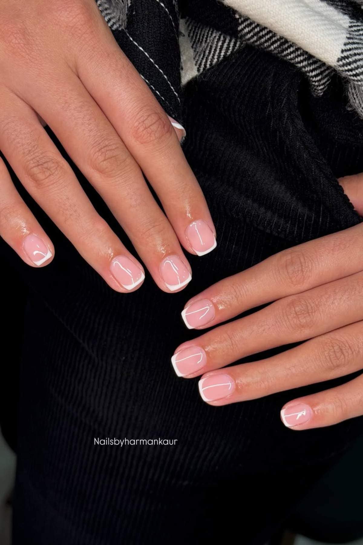 Close-up of hands with neatly manicured nails featuring a classic French tip design, with natural pink base and white tips.