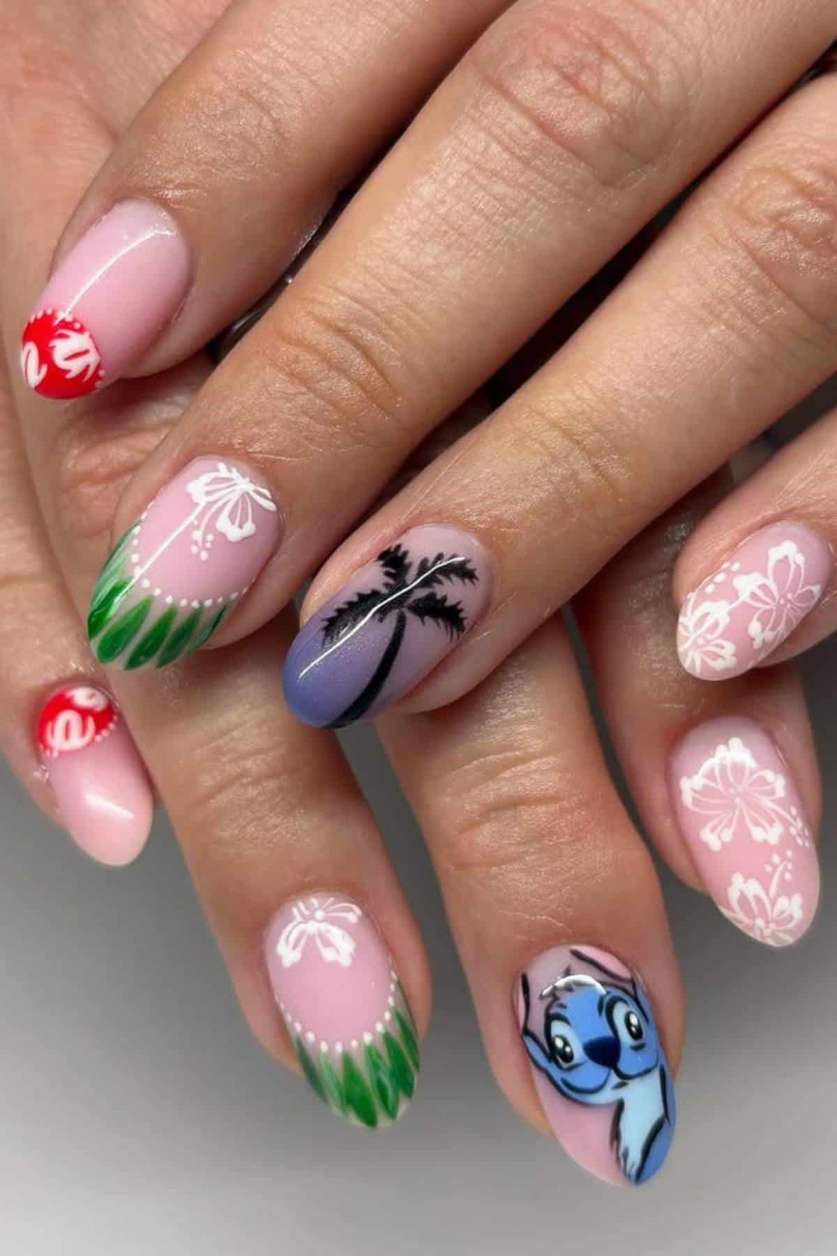A hand with nail art featuring hibiscus flowers, palm trees, green tips, and a cartoon character on a pink and purple gradient background.
