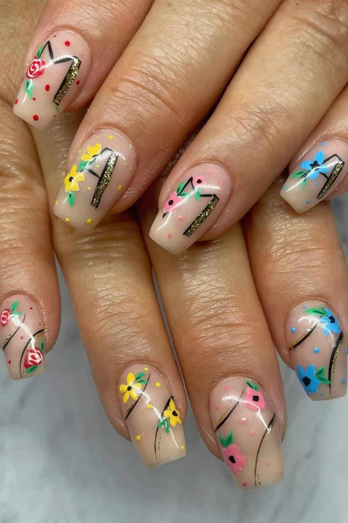 Fingernails with a nude base and colorful floral designs in blue, yellow, red, and pink, accented with fine black and gold lines.