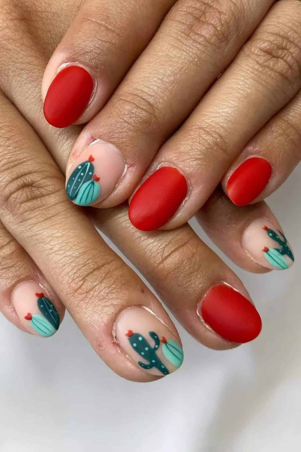 Hands with manicured nails; most nails are painted matte red, while some feature a cactus design on a nude base with small red accents.