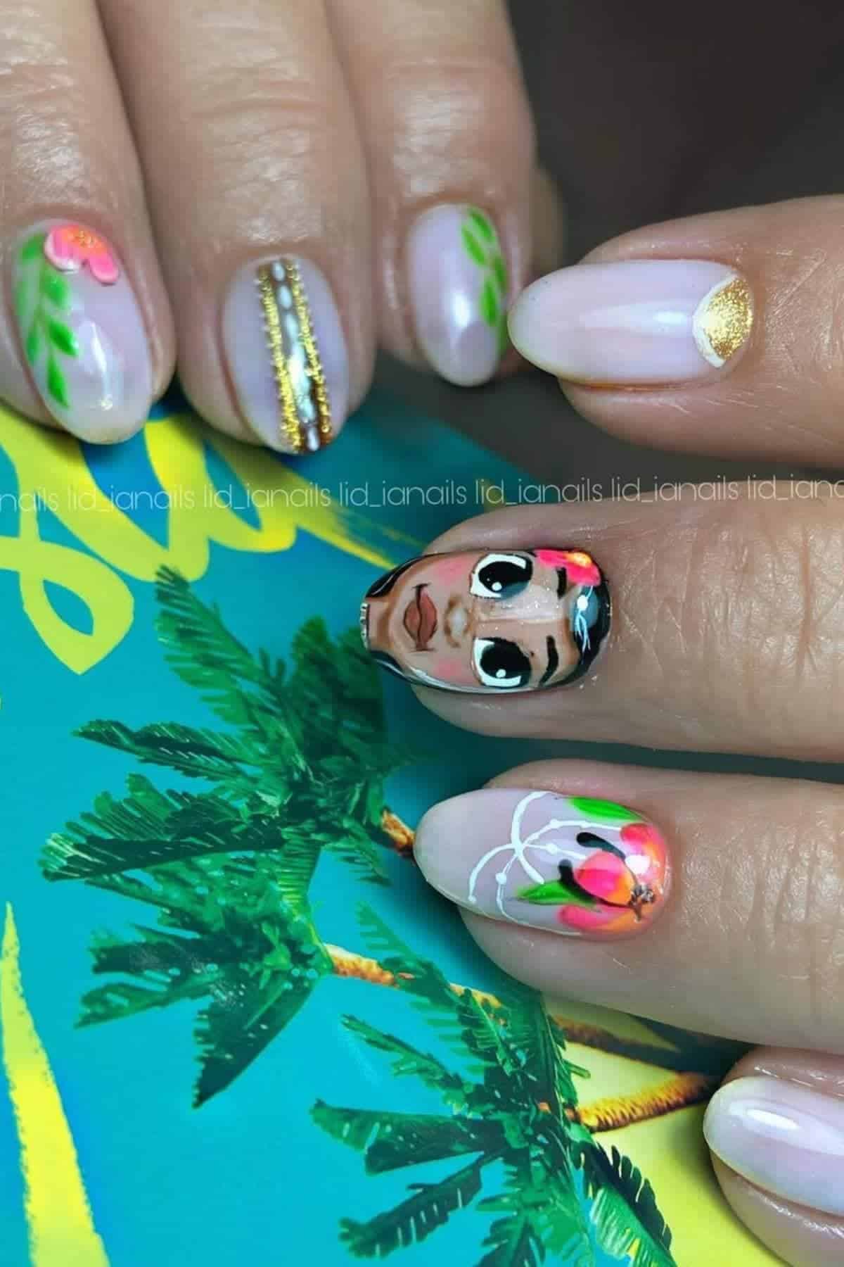 A hand with manicured nails featuring various designs, including a stylized face, floral patterns, gold accents, and stripes, placed against a tropical-themed background.