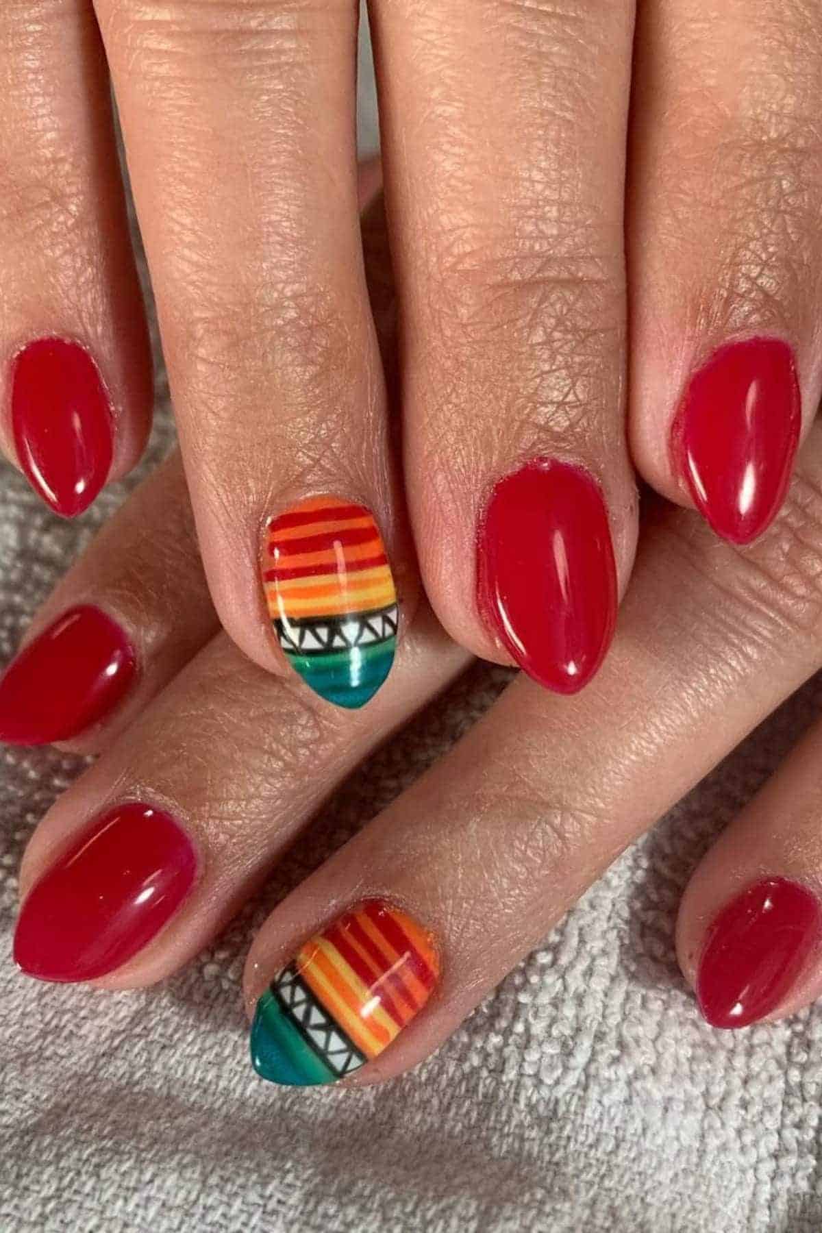 Hands with red nail polish; ring fingernail features a colorful geometric pattern with horizontal stripes and triangular shapes.