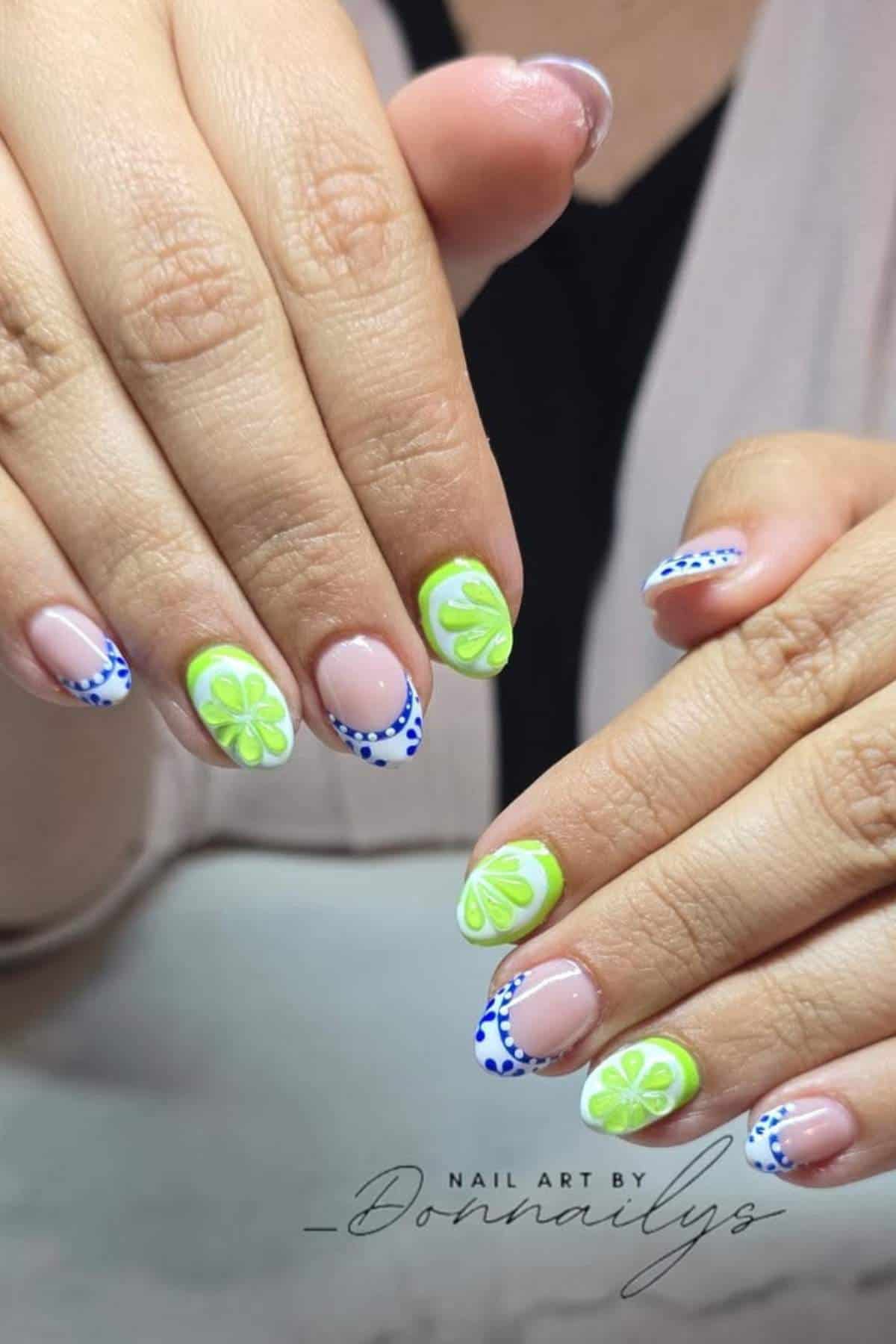 Close-up of hands with almond-shaped nails featuring neon green floral and blue dotted nail art on a nude base.