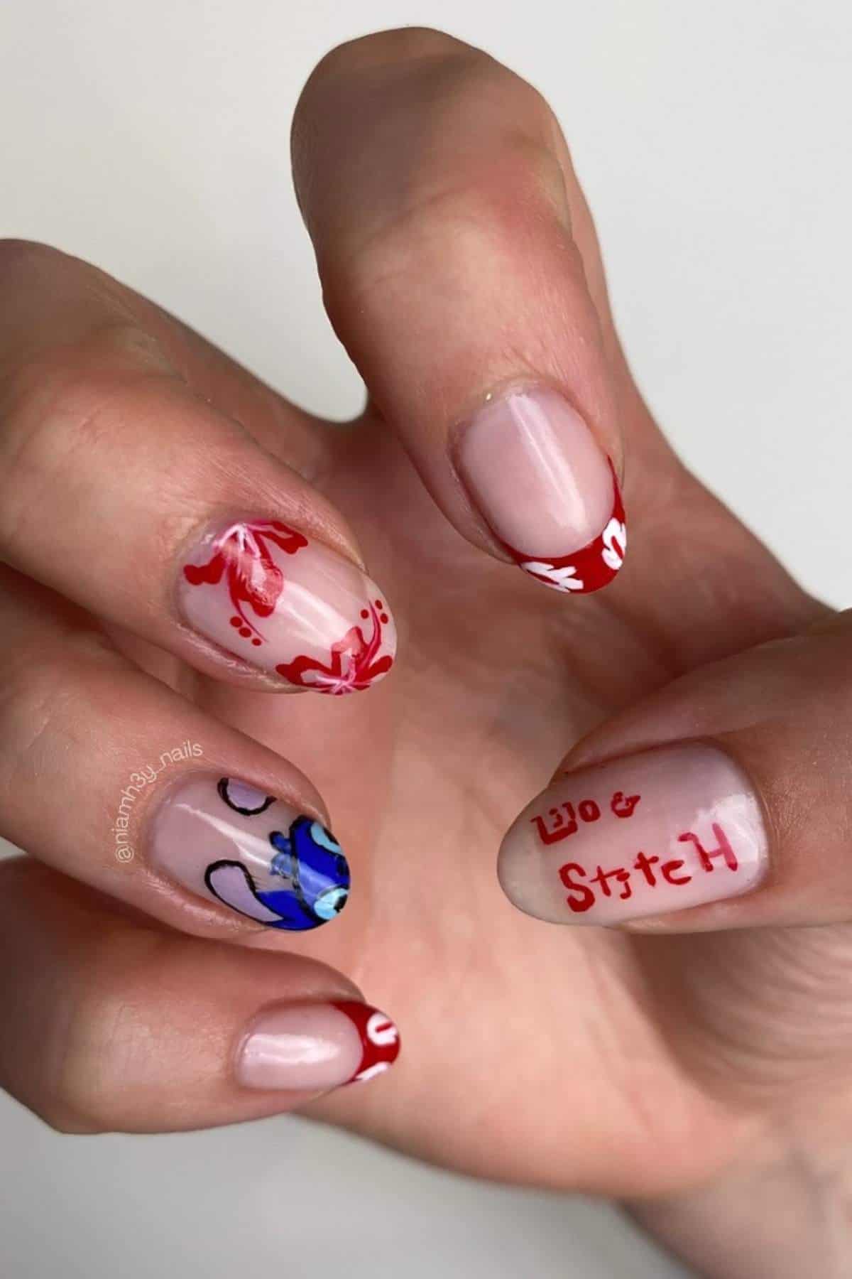 A hand with nail art featuring red floral designs, French tips, and a blue cartoon character with the text "Lilo & Stitch" on the thumb nail.