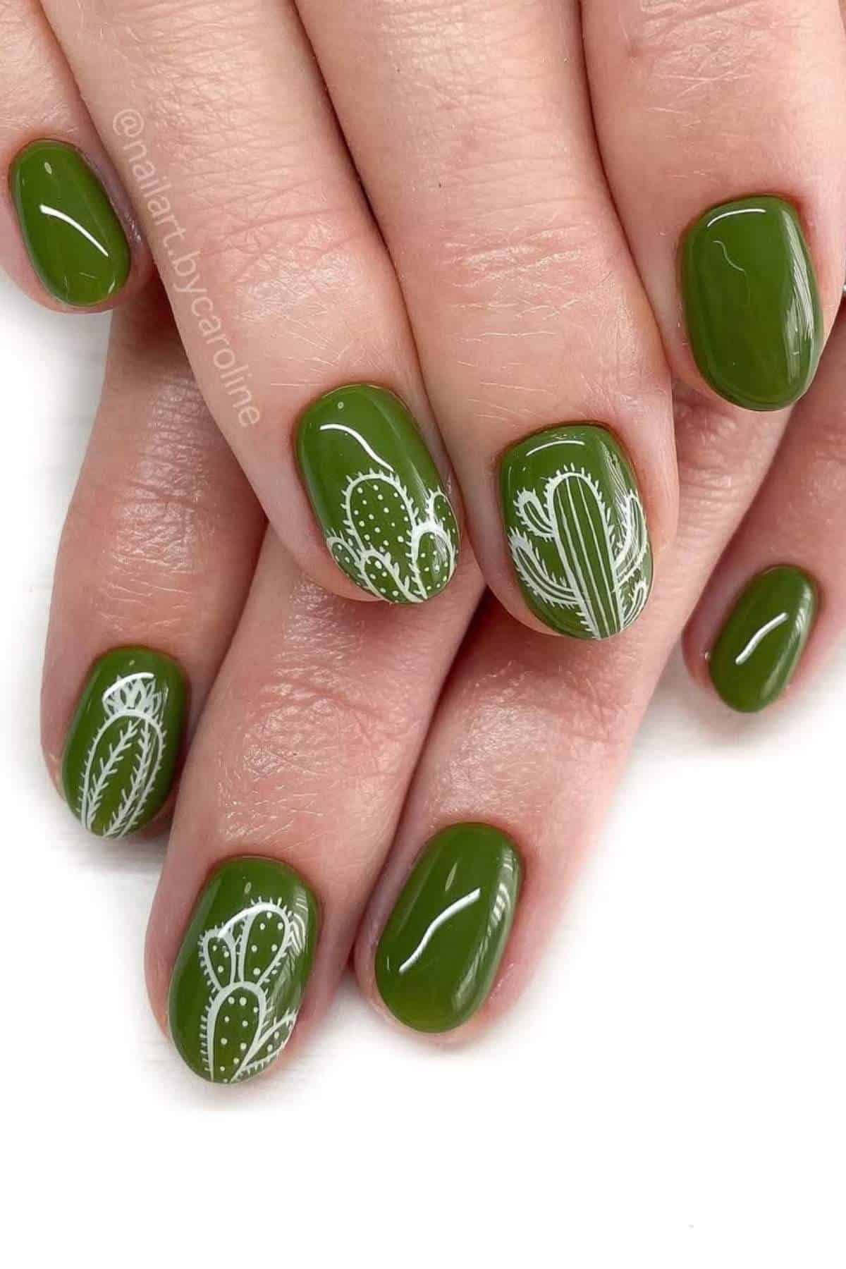 Fingernails painted glossy green with white cactus and leaf designs on some nails, shown on both hands.