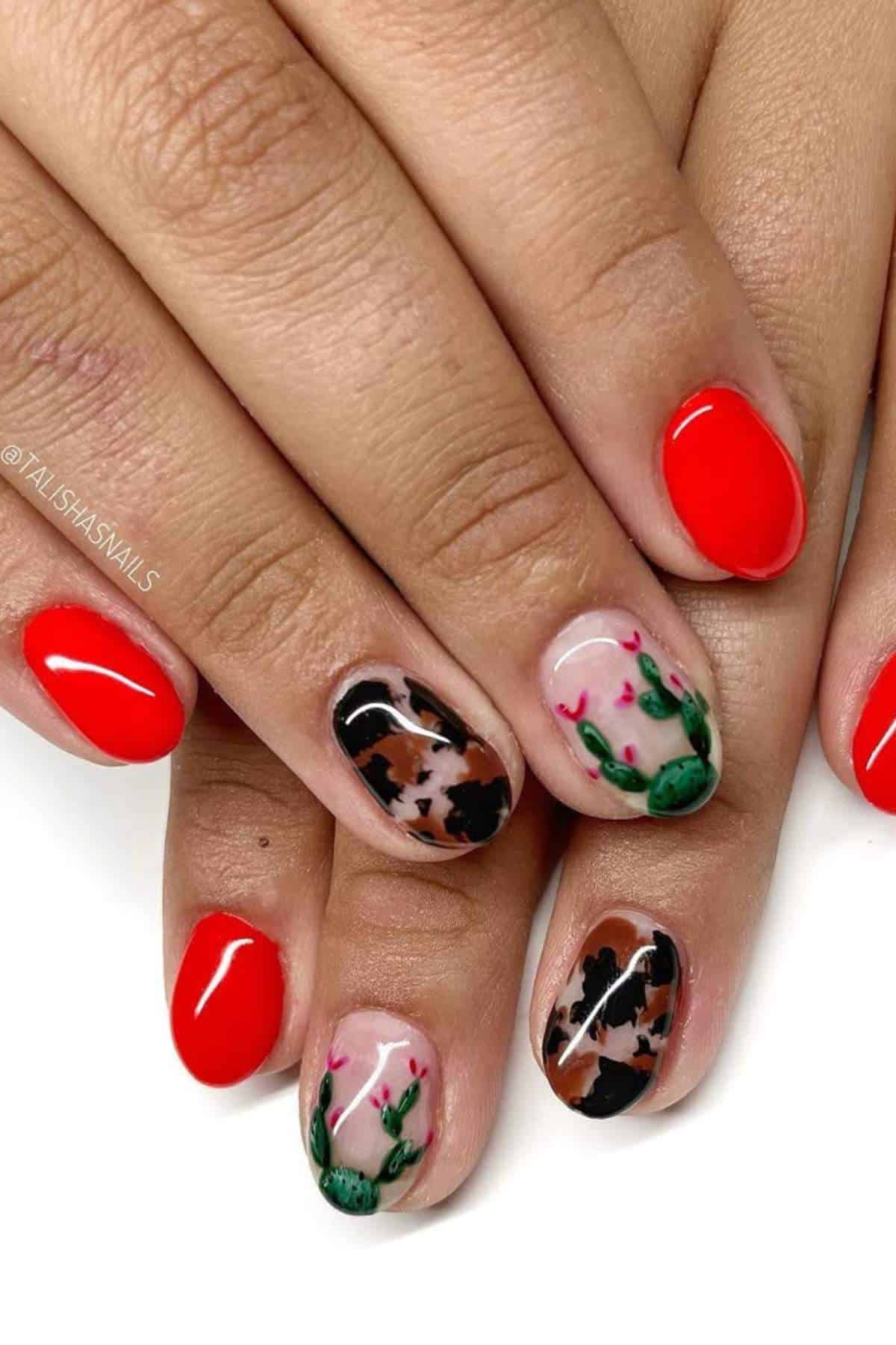 Hands with short nails; most are painted bright red, while two nails on each hand feature a design with animal print, green cactus, and pink flower details on a nude base.