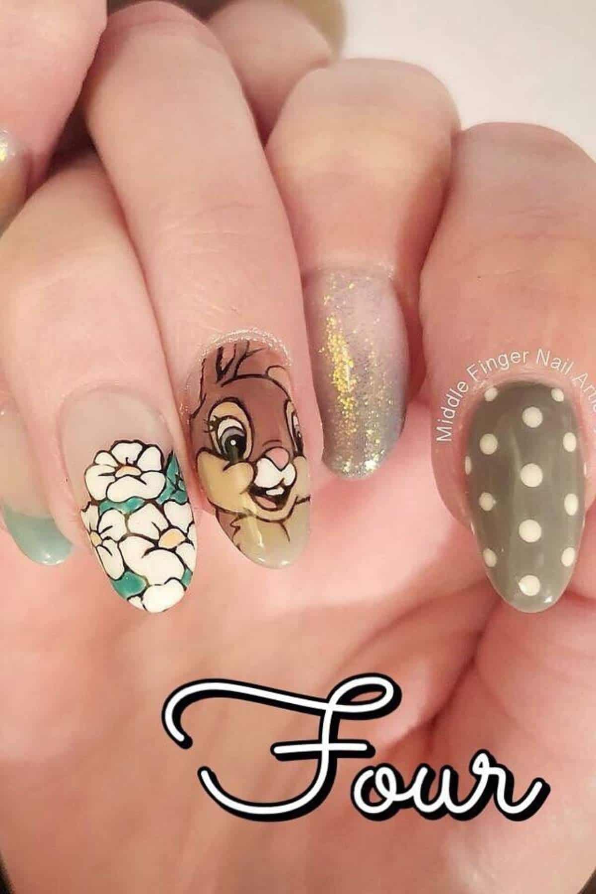 A hand with manicured nails featuring floral art, a cartoon bunny, glitter, and white polka dots on a gray background. The word "Four" is written at the bottom of the image.