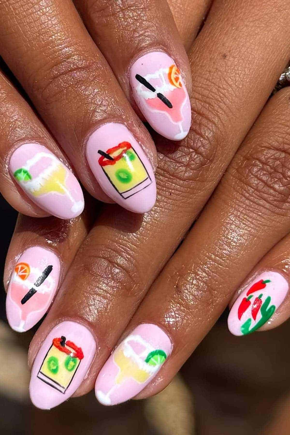 Close-up of fingernails with pink polish and colorful cocktail-themed nail art, including fruit garnishes and drink glasses on each nail.