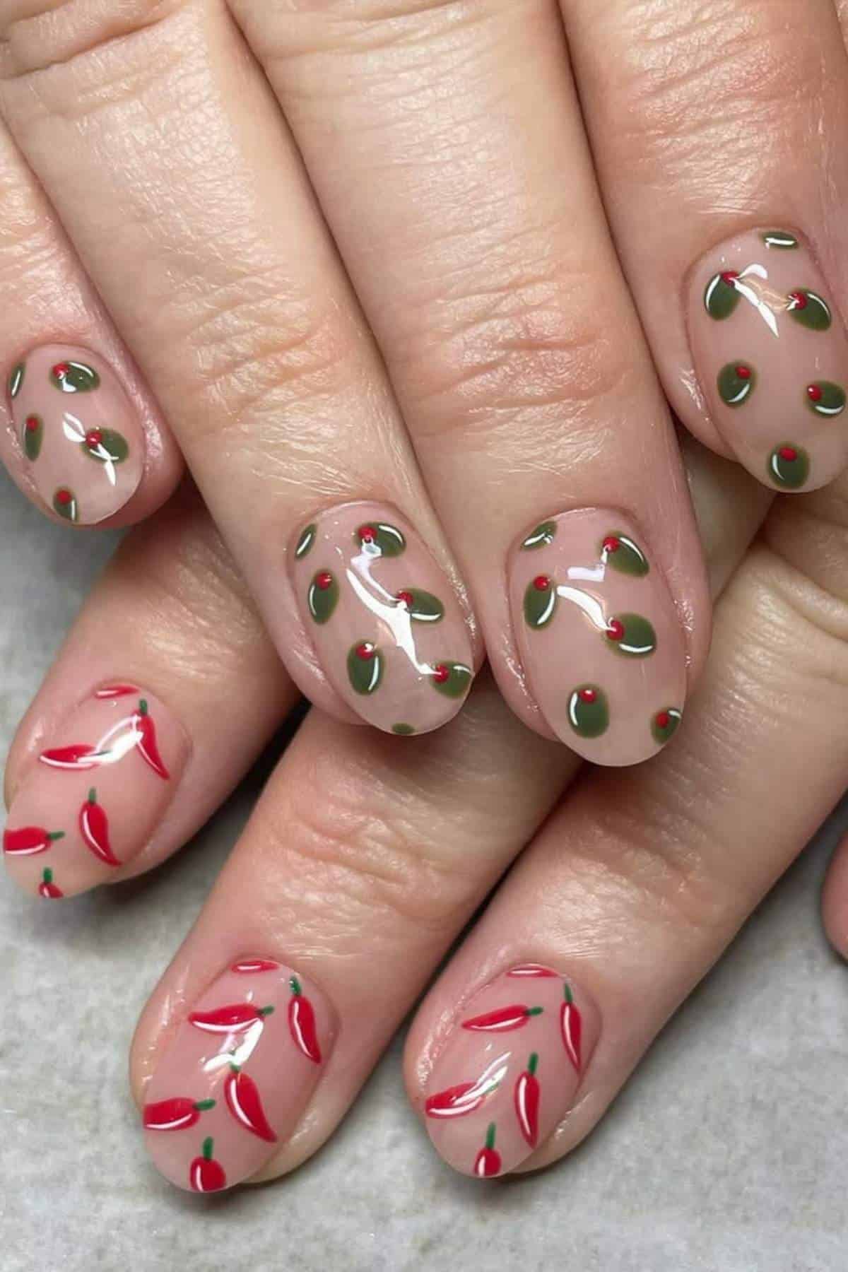 Fingernails with clear polish feature red chili pepper and green leaf nail art designs on each nail.