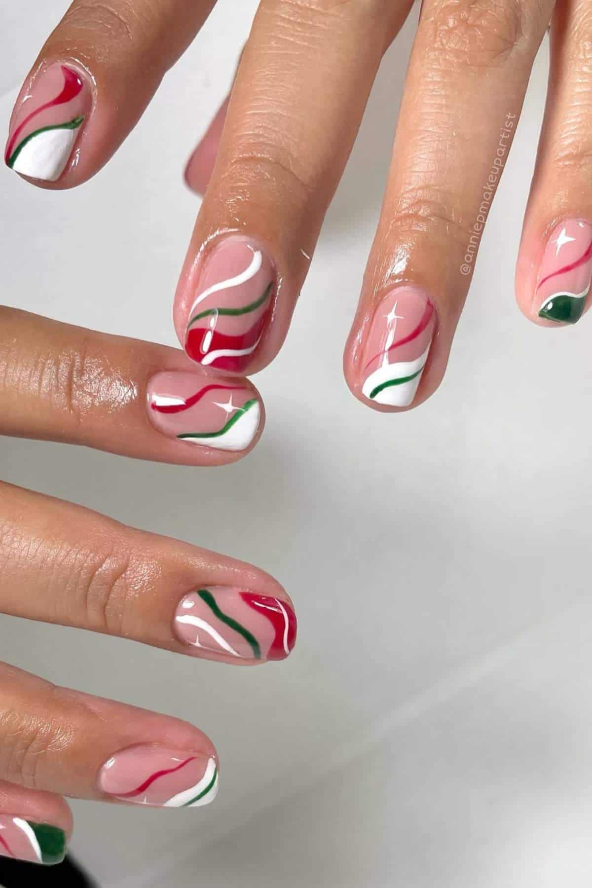 Fingernails with abstract wavy designs in red, white, and green on a natural base.