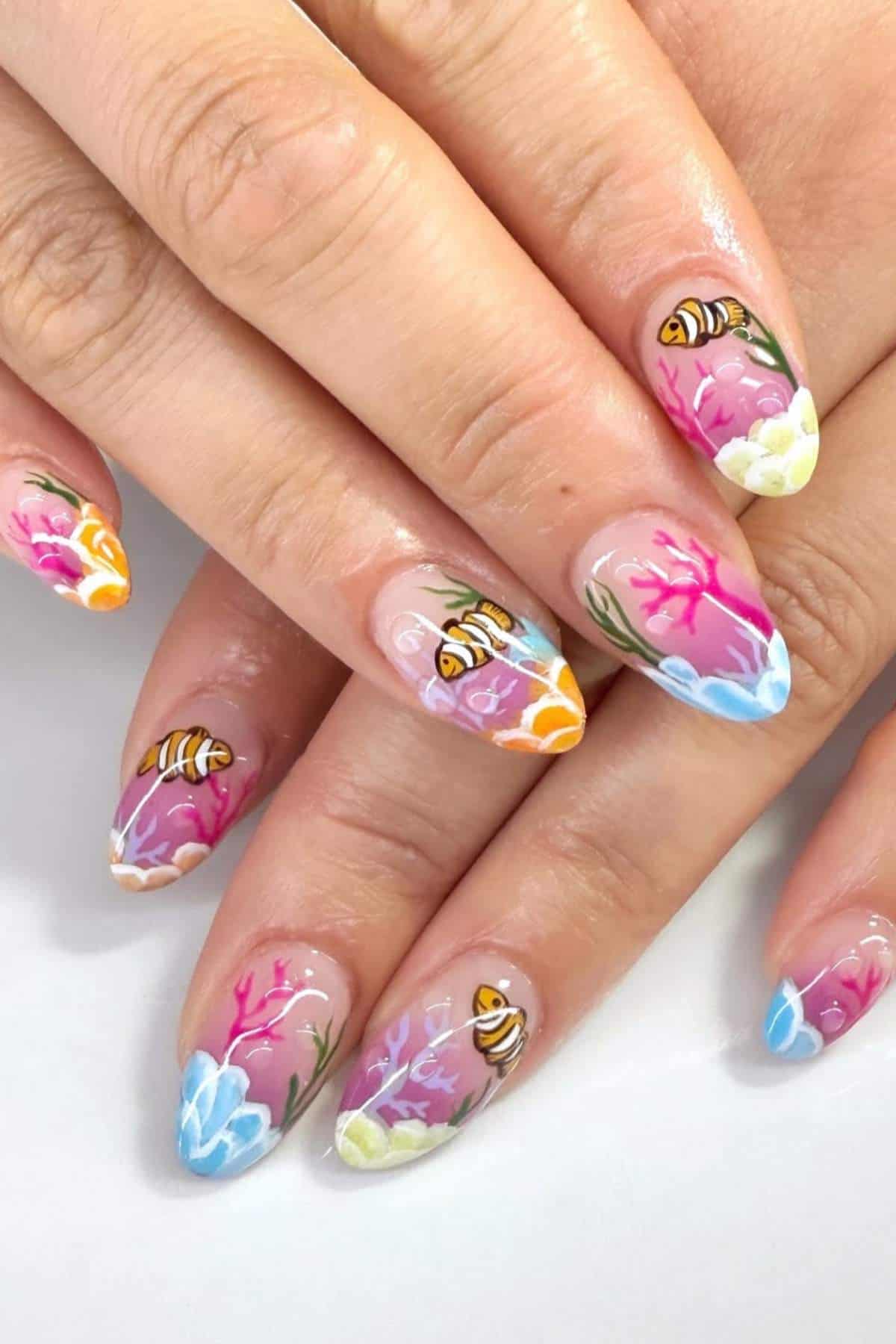 Fingernails with colorful floral and bee-themed nail art featuring pink, blue, yellow, and orange accents.