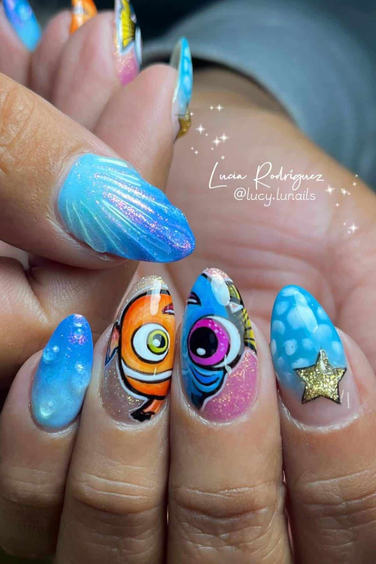 Close-up of manicured nails with colorful, ocean-themed designs, including cartoon fish, blue gradient, a shell, bubbles, and a gold star accent.