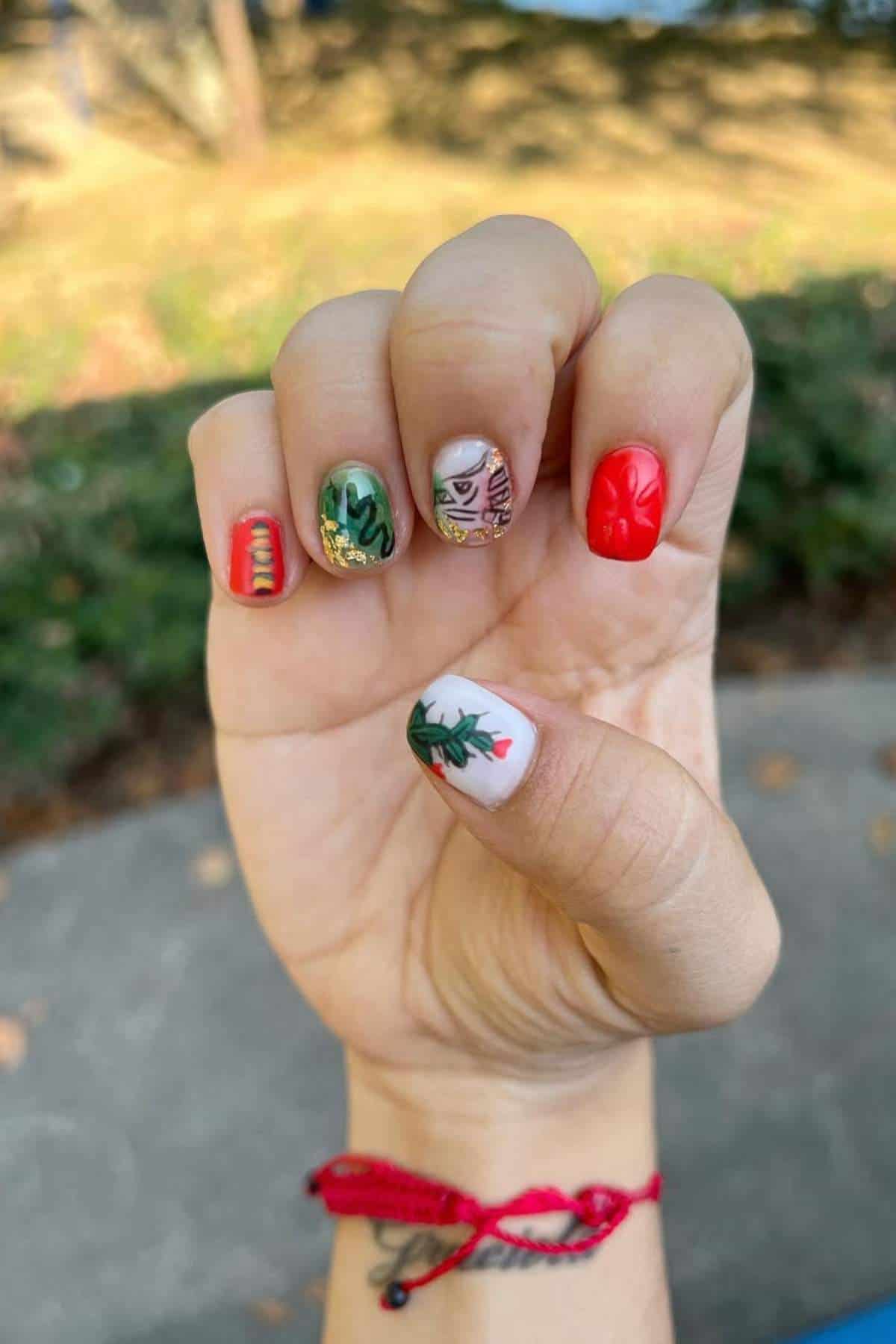 A hand with Cinco de Mayo-themed nail art shown outdoors.