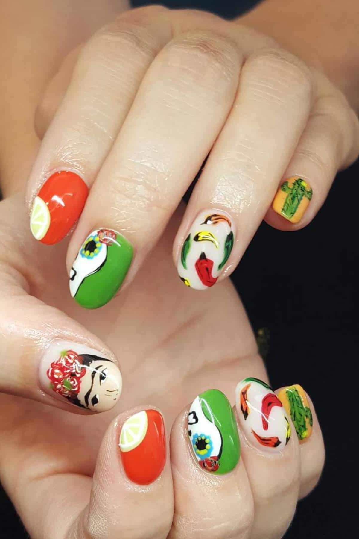 Hands with colorful nail art featuring designs such as chili peppers, lime slices, a woman's face, vegetables, and a taco on a black background.