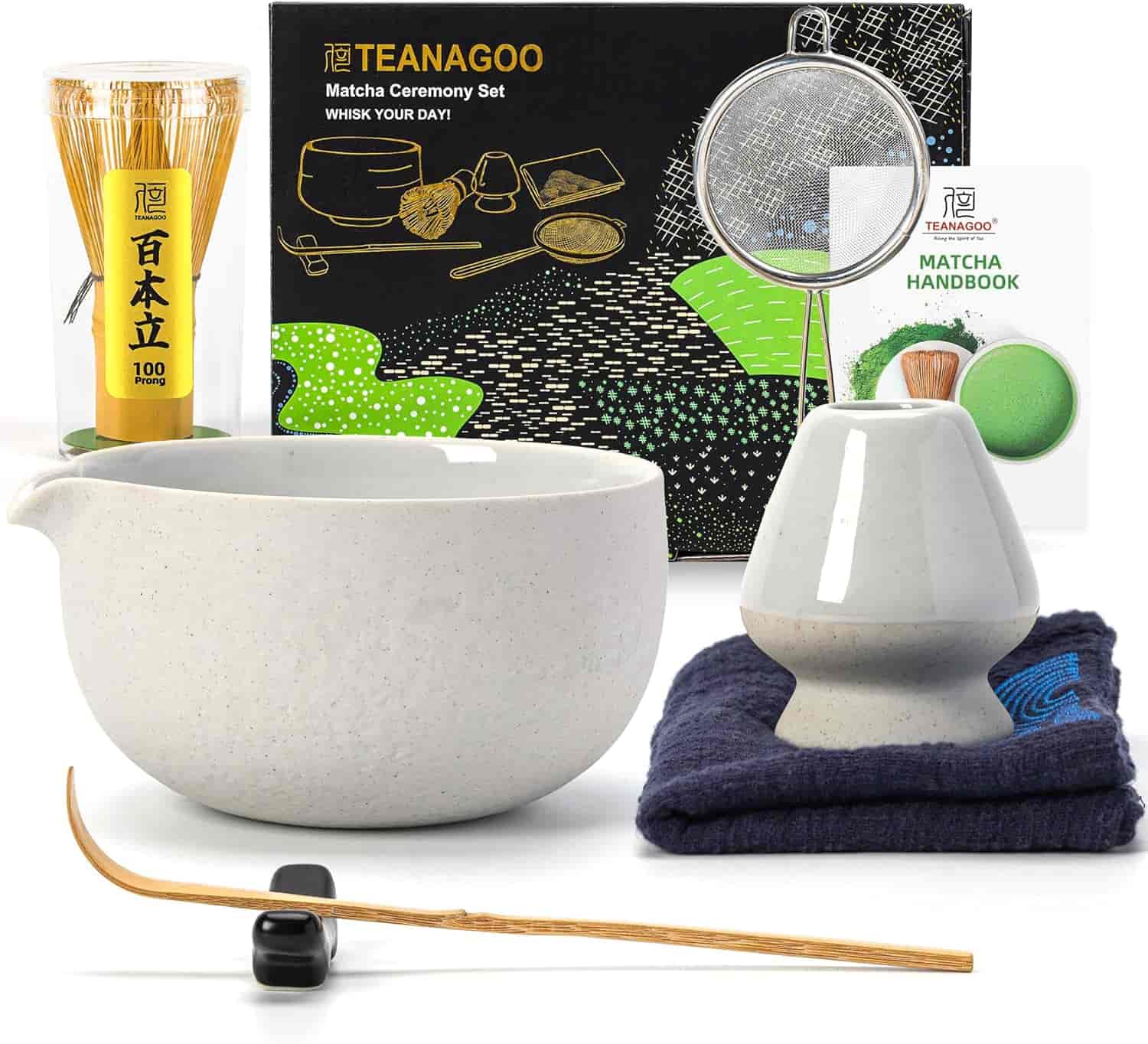 A matcha ceremony set with a whisk, whisk holder, strainer, bowl, scoop, measuring spoon, matcha handbook, and cloth, arranged in front of a TEANAGOO branded box.