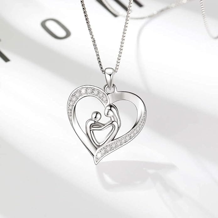 A silver heart-shaped pendant necklace featuring two abstract figures, resembling a parent and child, with embedded small clear stones on part of the heart.