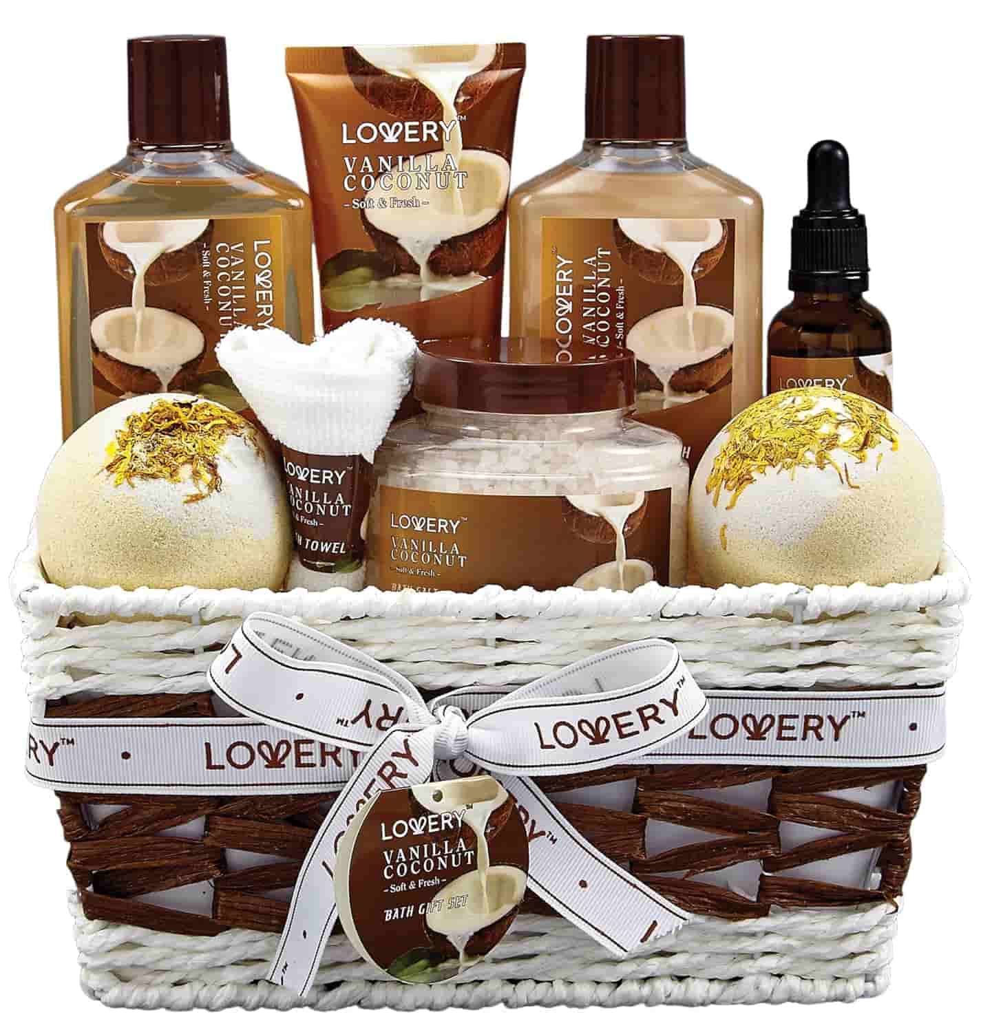 A white basket filled with Lovery Vanilla Coconut bath products, including lotions, bath bombs, oil, towel, and body scrub, tied with a ribbon.