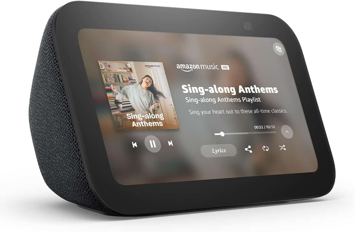 A black smart display shows an Amazon Music playlist titled "Sing-along Anthems" with a song playing and media controls visible on the screen.