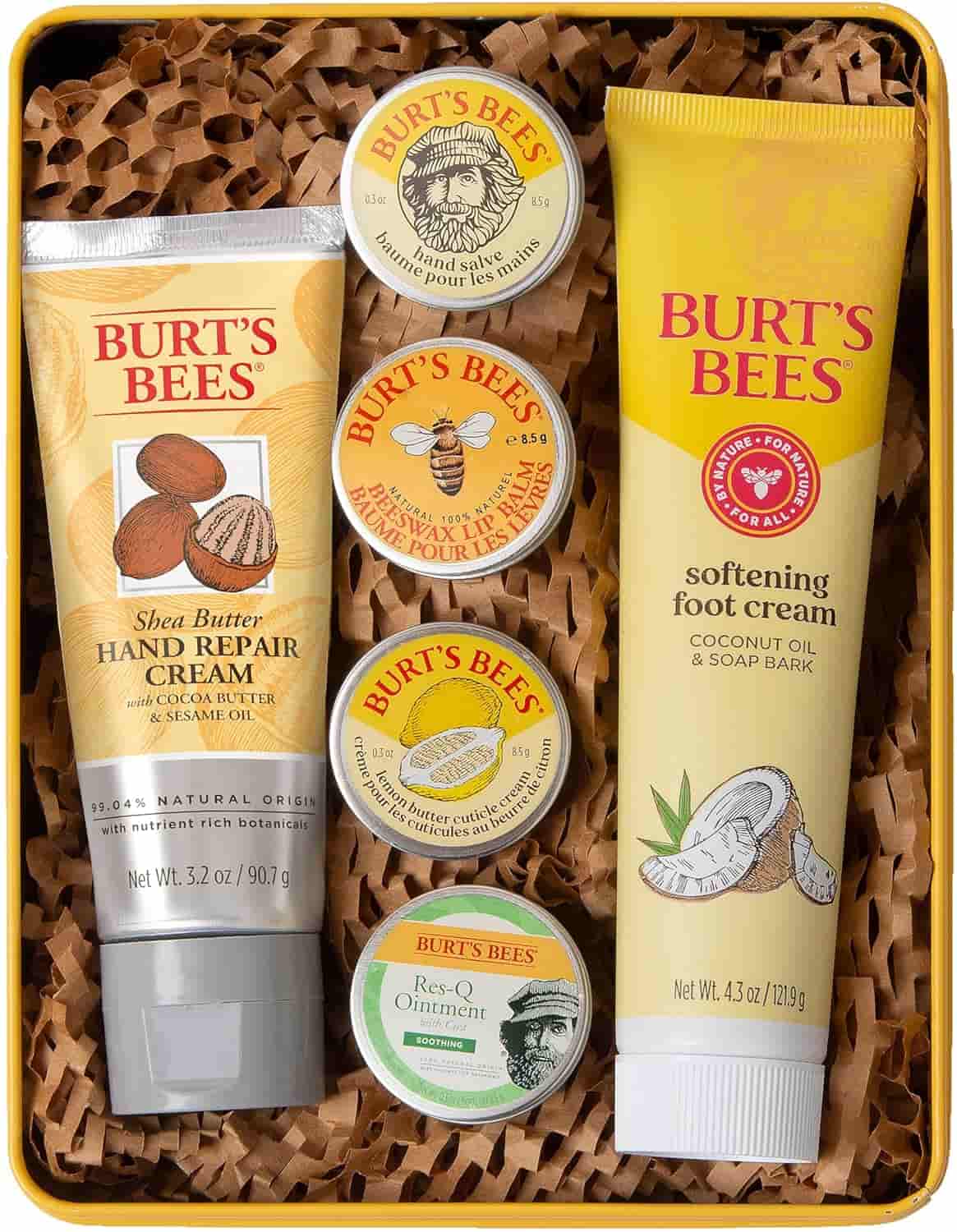 A gift set of Burt’s Bees skincare products, including hand cream, foot cream, ointment, and four lip balms, arranged on shredded brown paper in a box.