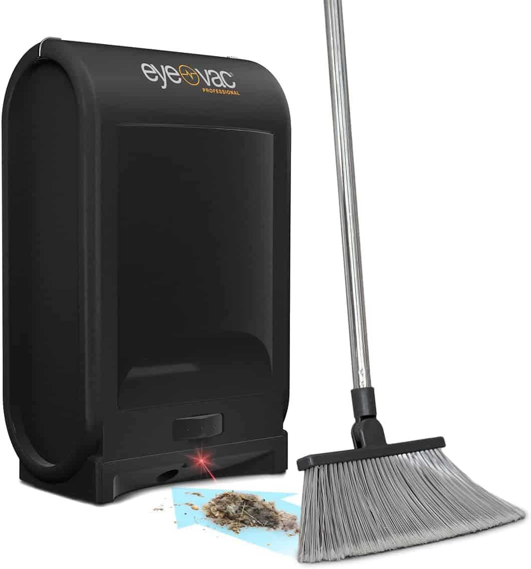 A black touchless vacuum (EyeVac) next to a broom sweeping debris toward its sensor-activated suction opening.