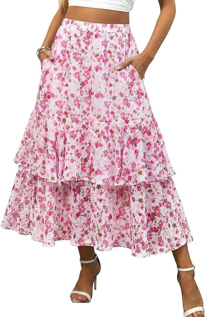 Woman wearing a white crop top and a pink floral tiered midi skirt with pockets and white heels.