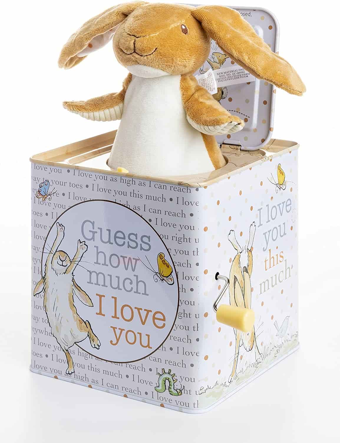A plush rabbit pops out of a decorated jack-in-the-box featuring illustrations and the phrases "Guess how much I love you" and "I love you this much.