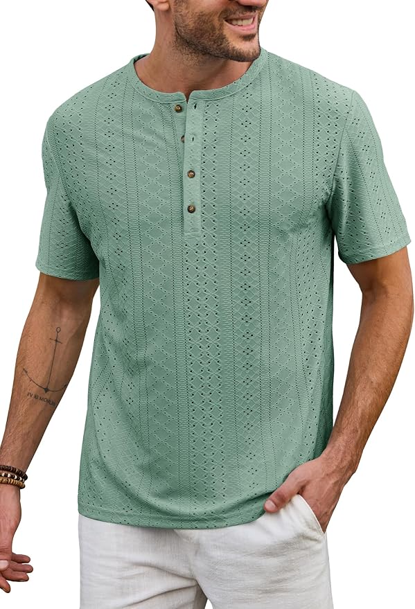 A man wearing a light green short-sleeve, textured henley shirt with buttons and white pants. The shirt features a subtle geometric pattern.